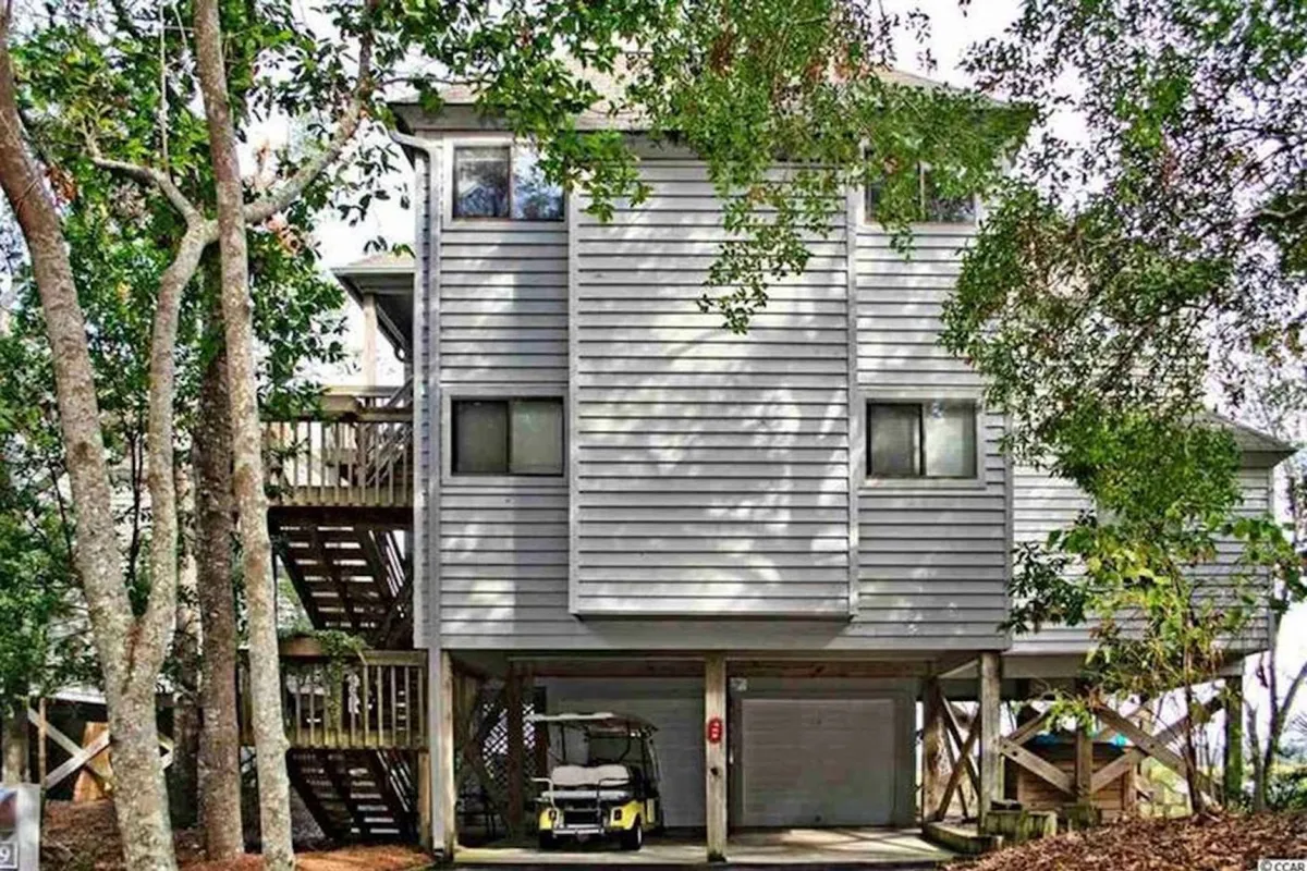 An exterior view of wooden staircases and deck spaces surrounded by trees, with a golf cart parked nearby. The scene suggests relaxation, outdoor gatherings, and exploration, all set in a peaceful and inviting atmosphere.