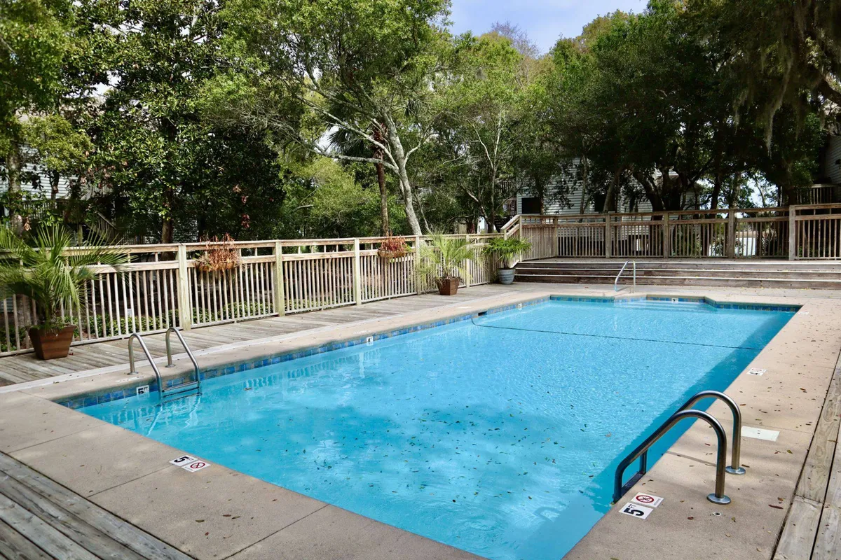 A sparkling community saltwater pool sits surrounded by a stylish wooden deck and shaded by mature trees. Comfortable seating and ample space for sunbathing or socializing make this a welcoming amenity for guests seeking relaxation or a refreshing swim.